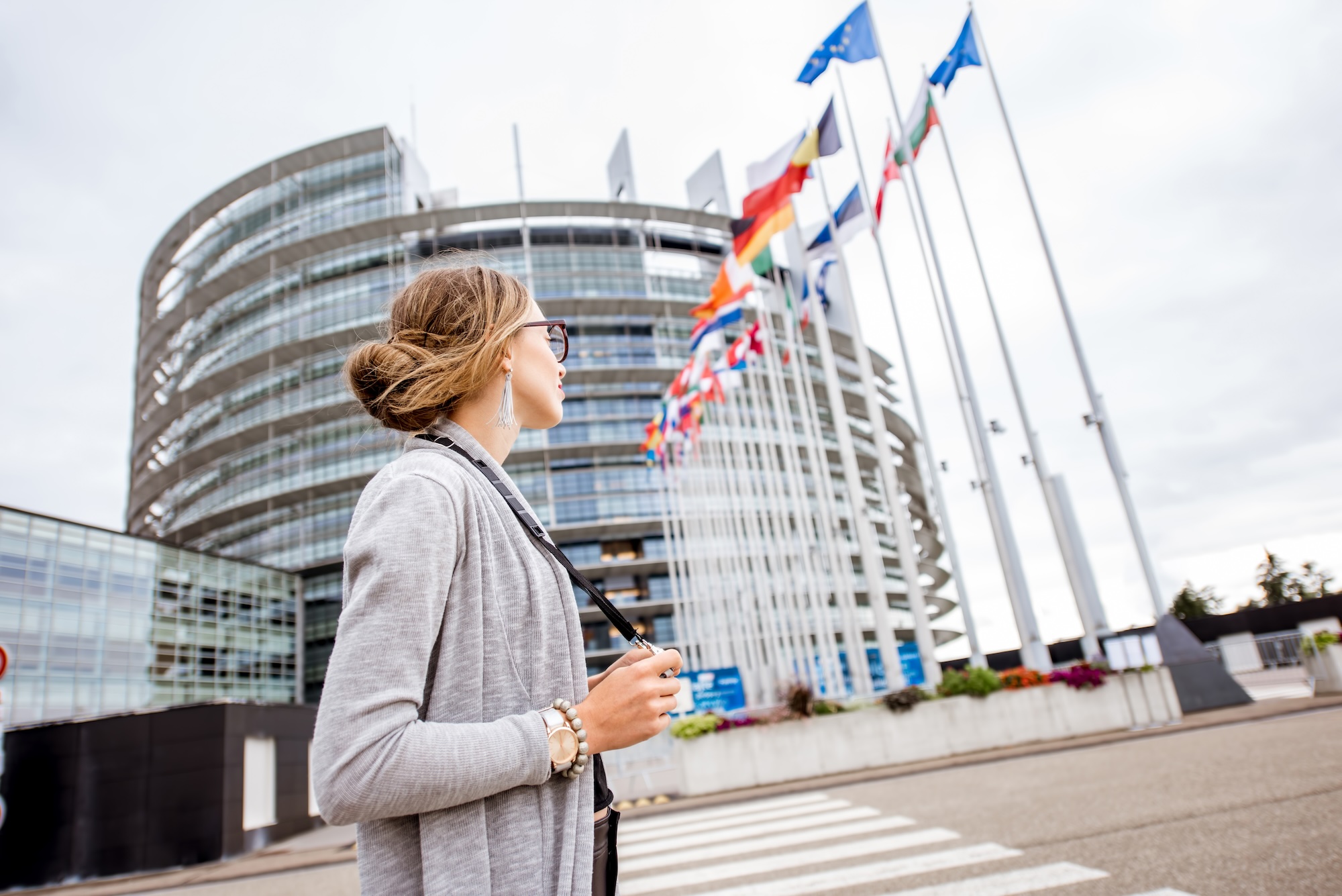 Young woman tourist standing with photo camera in front of the European parliament building in Strasbourg, France